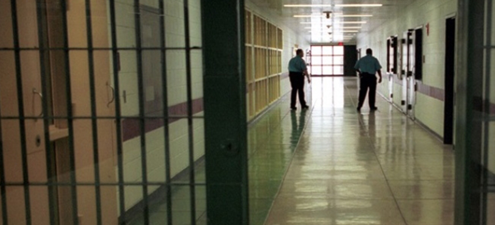 Günışığının içeriye sızdığı bir cezaevi koridorunda bir gardiyan yürüyor.