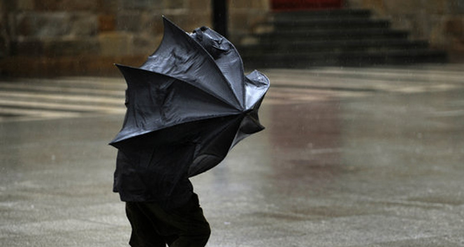 Siyah giyinimli bir kişi şemsiyesini açmış fırtınaya karşı yürümeye çalışıyor