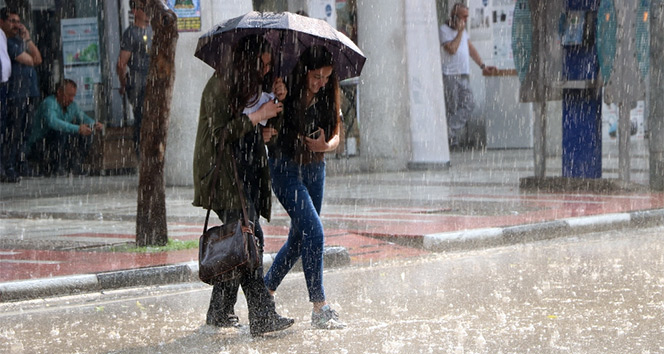 Bir şemsiye altında iki kişi yağmurda yürüyor.