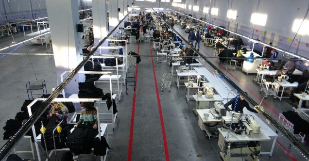 Tekstil fabrikası içersinde sıra sıra dizilmiş tezgahlar bulunuyor.