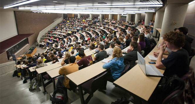 Üniversite amfisi içerisinde öğrenciler amfinin arkasından sıralarda otururken görüntüleniyor