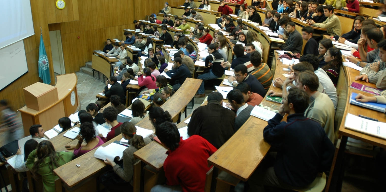 Üniversite amfisinde öğrenciler sıralarda oturuyor.