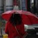 Kırmızı şemsiye taşıyan bir kadın yolda yürüyor