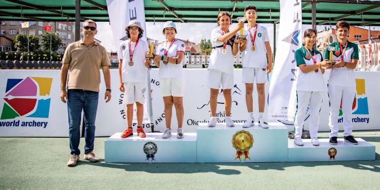 Beyaz formalı sporcular, ödül seramonisinde kupalarıyla poz veriyor