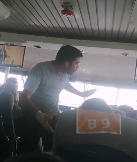 Deniz otobüsü içinde işçi eldivenli bir kişi ayakta duruyor