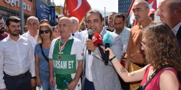 CHP Bursa İl Başkanı İsmet Karaca elinde mikrofonla kalabalığın arasında konuşuyor. Karaca'nın yanında Bursaspor forması giyen amigo Ardiles'in boynunda madalya var