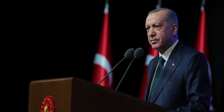 Recep Tayyip Erdoğan, üzerinde Cumhurbaşkanlık forsu olan kürsüde duruyor
