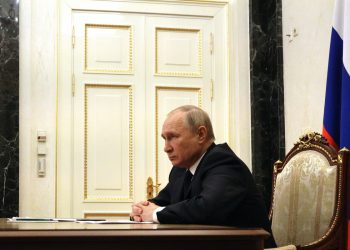 Rusya Devlet Başkanı Putin bir masada ellerini bir birine geçirmiş şekilde oturuyor