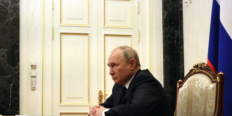 Rusya Devlet Başkanı Putin bir masada ellerini bir birine geçirmiş şekilde oturuyor