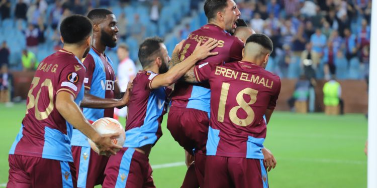 Bordo mavi formalı beş futbolcu bir birlerine sarılarak gol sevinci yaşıyor