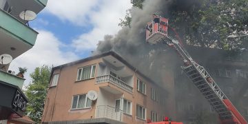 Apartmanın çatı katında çıkan yangında dumanlar yükselirken, itfaiye personeli yangına müdahale ediyor.