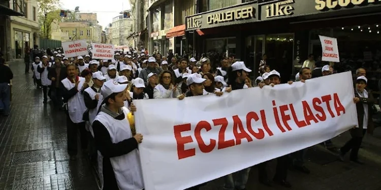 Eczacılar, "Eczacı iflasta" yazılı pankart arkasında yürüyüş yapıyor.