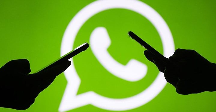 Yeşil renkli WhatsApp logosunun önünde iki tane silüet şeklindeki el telefon tutuyor
