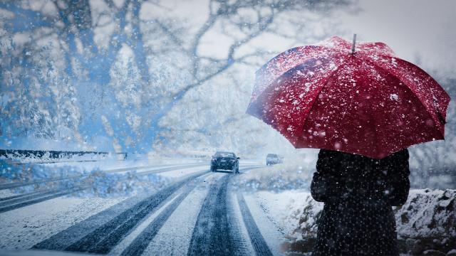 Kar yağışı ve soğuk bir hava hakim. Yağış devam edereken yol kenarında kırmızı şemsiyeli bir insan yürüyor