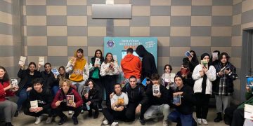 Metroda toplanan öğrenciler ellerinde tuttukları kitabı okuyor.