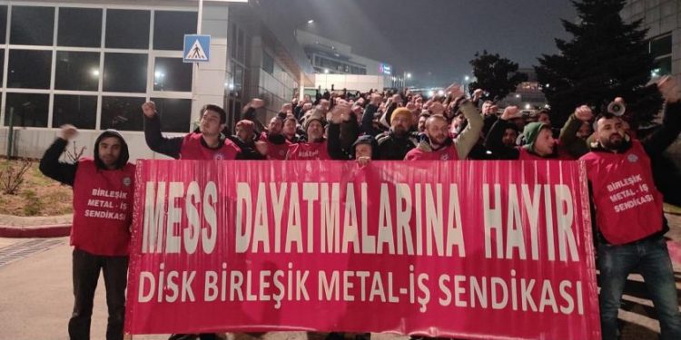 MESS dayatmalarına hayır pankartı arkasında bir araya gelen Birleşik Metal İş üyesi işçiler eylem yapıyor.