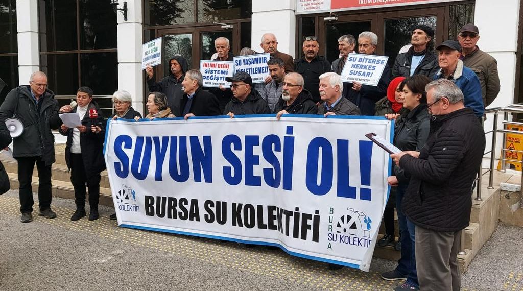 Bursa Su Kolektifi üyelerinin ellerinde 'Suyun Sesi Ol' yazılı pankart bulunuyor.