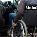 Bir otomobilin sürücü koltuğunun yanında tekerlekli sandalyede biri oturuyor.